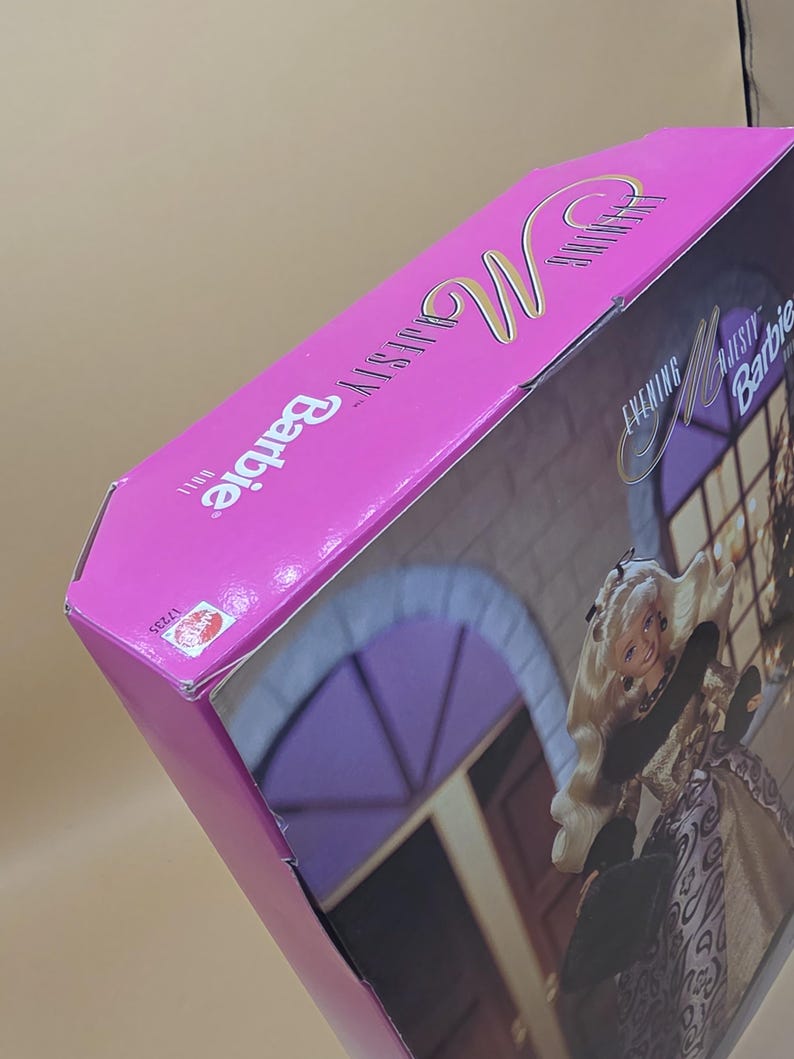 以下が含まれることがあります： Evening Majesty Barbie人形用の鮮やかなピンク色の長方形の段ボール箱。パッケージにはBarbieのロゴとEvening Majesty Dollの文字が記載されています。側面には小さな赤いMattelのロゴと番号17235が印刷されています。