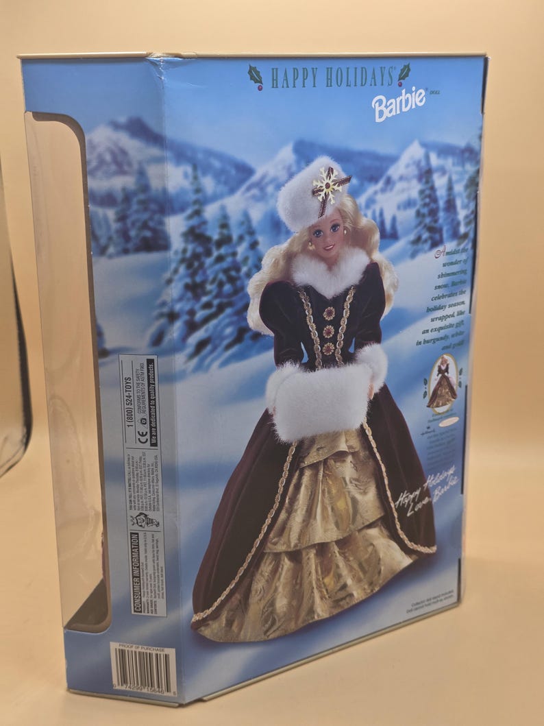 May include: A Happy Holidays Barbie doll in a box, featuring a blonde doll wearing a burgundy velvet gown with white faux fur trim, a matching hat with a snowflake ornament, and a gold skirt, set against a snowy winter landscape background.
