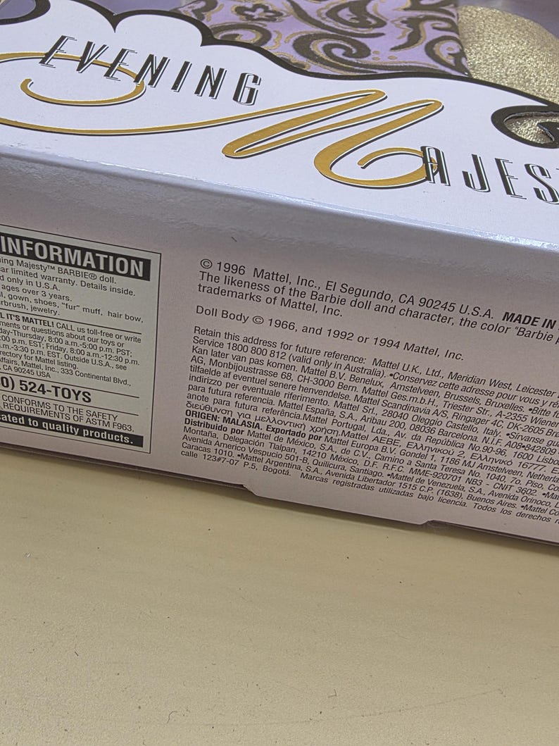以下が含まれることがあります： 黒と金の筆記体でEvening Majestyと書かれた白い段ボール製の玩具用パッケージ箱。箱には詳細な製品情報、1996年の著作権表示、およびMattel, Inc.の連絡先情報が黒い文字で印刷されています。