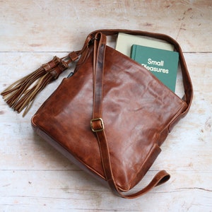 tan leather handbag with large 
tassel, handle and crossbody strap