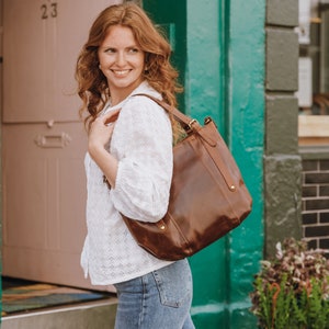 model wearing large brown leather shoulder bag