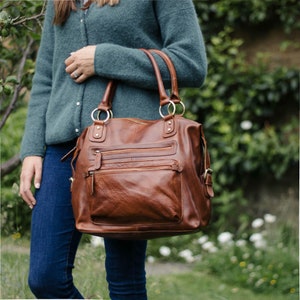 tan leather double front zip pocket tote held in models arm