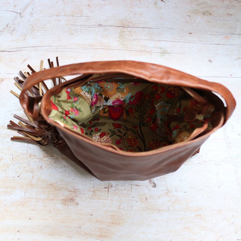 tan soft leather hobo tote with floral print fabric lining, large tassel and handle