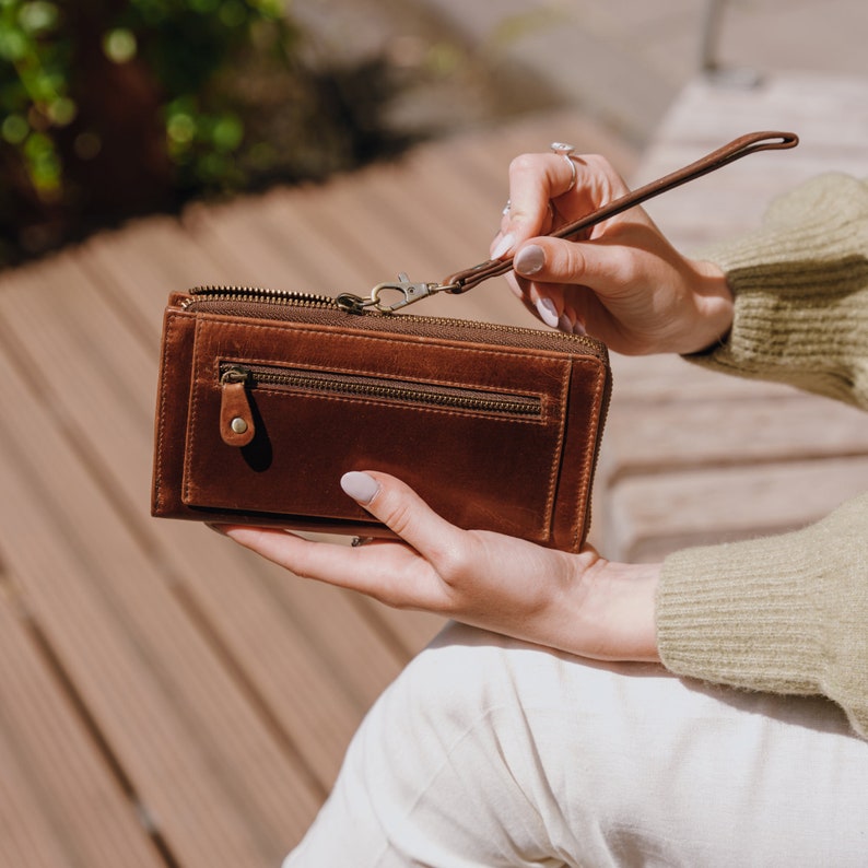 large brown leather womans wallet with zip closure, front pocket and wristlet strap