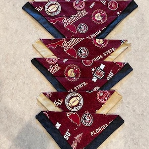 May include: A set of ten maroon and gold fabric dog bandanas with a Florida State Seminoles theme. The bandanas feature a variety of logos and designs, including the FSU logo, the Seminole head, and the words "Florida State" and "Seminoles".