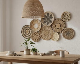 Könnte beinhalten: Ein Esszimmer mit einem Holztisch, gedeckt mit Geschirr und Pflanzen. Über dem Tisch hängt eine gewebte Pendelleuchte. Die Wand ist mit einer Sammlung gewebter dekorativer Teller in verschiedenen Größen und Mustern geschmückt, die einen natürlichen, böhmischen Stil schaffen.
