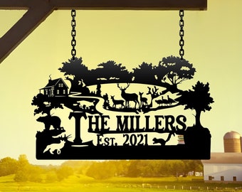 May include: Black metal sign featuring a silhouette of a cabin, trees, and deer. The sign reads "The Millers Est. 2021".