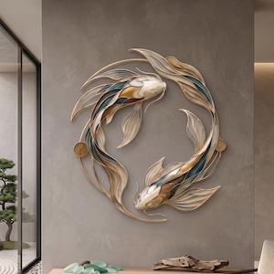 Pode incluir: Uma escultura de parede circular apresentando dois peixes koi nadando em um círculo contínuo. Os peixes são representados em tons de creme, dourado e azul-petróleo profundo com barbatanas fluidas e em camadas que criam movimento.