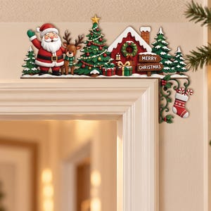 Può includere: Una decorazione natalizia per angolo porta con Babbo Natale, una renna, alberi di pino decorati, una casa rossa con ghirlanda e regali. Un cartello in legno riporta la scritta MERRY CHRISTMAS. Un ornamento verde a volute regge una calza.