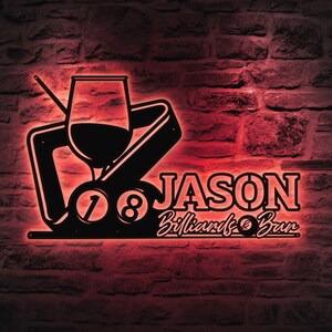 May include: Black metal wall art with a red neon glow, featuring a wine glass, pool rack, and the numbers 7 and 8. The text reads "JASON Billiards & Bar" in a stylized font, perfect for a home bar or game room.