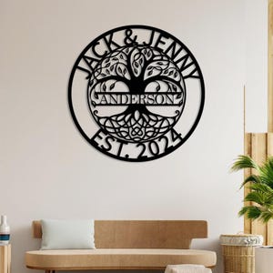 May include: Black metal wall art featuring a stylized tree with intricate branches and roots. The names "Jack & Jenny Anderson" and "Est. 2024" are inscribed around the tree.
