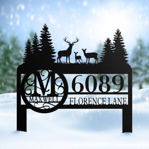 May include: Black metal address sign featuring a deer family silhouette and evergreen trees. The sign displays the address 6089, the name Maxwell, and Florence Lane.