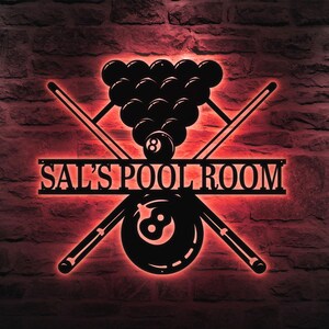 Può includere: Un cartello in metallo nero con un design di stecca da biliardo e il testo "SAL'S POOL ROOM". Il cartello presenta un triangolo di palle da biliardo con una grossa 8-ball al centro.