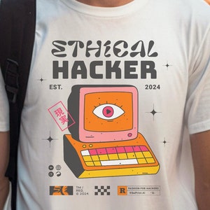 Könnte beinhalten: Weißes T-Shirt mit einer Retro-Computergrafik und dem Text "Ethical Hacker" mit den Jahren "EST. 2024".