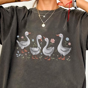 Whimsical Geese Unisex Tee, White Birds Floral Shirt, Pastel Colors Nature Top, Cross-Hatch Texture, Hand-Drawn Design, Soft Lighting, Cute