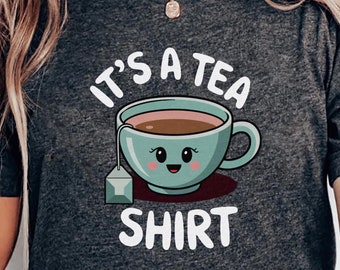 May include: A dark gray t-shirt with the text "It's a Tea Shirt" and a cartoon illustration of a teacup with a smiling face.