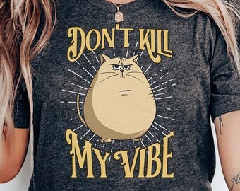 Op de afbeelding: Een donkergrijs T-shirt met een cartoonkat en de tekst "Don't Kill My Vibe".
