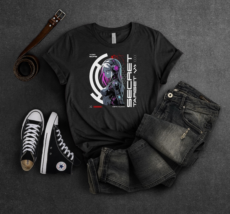 May include: Black t-shirt with a graphic design of a woman with headphones and a futuristic design. The text "SECRET TARGET" is on the right side of the design.