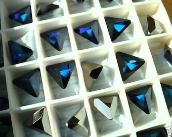 May include: A close-up view of a tray filled with various triangular-shaped rhinestones. The rhinestones are arranged in rows and are all a dark blue color. The tray is white and has a grid pattern.