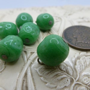 May include: Five green glass beads with a metallic silver finish. The beads are round and have a smooth, glossy surface. The beads are about the size of a US penny.