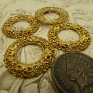 May include: Four gold-toned metal rings with intricate filigree designs. The rings are approximately the size of a US penny.