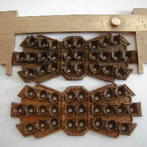 May include: Two antique metal pieces with a decorative design and multiple holes. The pieces are brown and have a worn look.