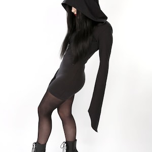 May include: A black hooded dress with long sleeves and platform boots. The dress has a fitted silhouette and a hood that covers the head. The boots are black, lace-up, and have high heels. The website address www.metalbecgear.com is visible.