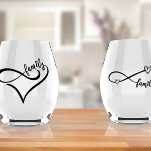 Könnte beinhalten: Zwei klare Weingläser aus Glas mit schwarzen Unendlichkeitszeichen und dem Wort "Familie" darauf gedruckt. Ein Glas hat eine Herzform innerhalb des Unendlichkeitszeichens, während das andere zwei kleine Herzen hat.