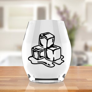 May include: A clear glass wine glass with a black and white sticker of three melting ice cubes.