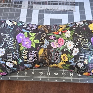 May include: A floral reading pillow with a black background. The pillow features colorful flowers, including sunflowers, tulips, and daisies, along with butterflies and script text. The text includes phrases like "You can grow your own way."