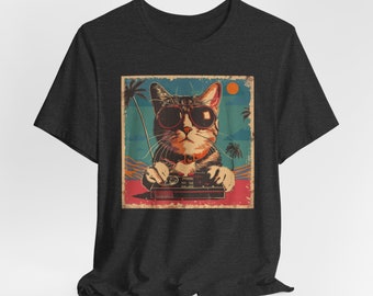 Puede incluir: Una camiseta gris carbón de manga corta con un estampado gráfico cuadrado de un gato con gafas de sol oscuras y un collar naranja. El gato sostiene un mando de videojuego negro sobre un fondo de palmeras, un sol y una playa.