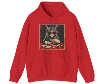 May include: A bright red hooded sweatshirt featuring a centered graphic print of a gray tabby cat wearing red sunglasses. The cat is depicted sitting at a table playing a card game with several playing cards and a red poker chip visible.
