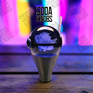 May include: A clear, spherical soda knob with a blue, glowing creature design inside. The knob sits on a silver-coloured base. The text "SODA KNOBS" is displayed in black above the knob.