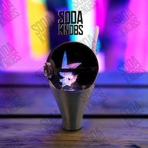 Peut inclure: Un bouton de soda décoratif avec un dessus sphérique noir orné d'un motif de fée lumineuse. Le bouton a une base argentée et le texte "SODA KNOBS" est affiché au-dessus.