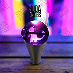 May include: A custom soda knob featuring a purple and white Mewtwo design within a clear, spherical orb. The knob is set on a silver base. The text "SODA KNOBS" is displayed above the knob.