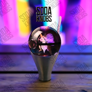 May include: A clear, spherical soda knob with an interior design and a silver-coloured base. The knob has a black band and a red accent. The text "SODA KNOBS" is displayed above the knob in black.