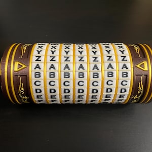 Può includere: Un puzzle cilindrico marrone e dorato con anelli rotanti che mostrano lettere. Gli anelli presentano le lettere A, B, C, D, E, X, Y e Z in bianco su sfondo oro. Sono visibili decorazioni e dettagli a forma di freccia.