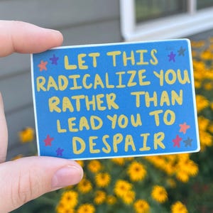 May include: A rectangular sticker with a blue background and the text "LET THIS RADICALIZE YOU RATHER THAN LEAD YOU TO DESPAIR" in yellow and white. The sticker is decorated with blue and yellow stars.