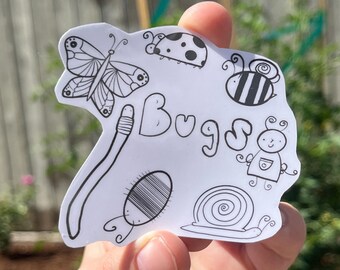 Peut inclure: Un autocollant blanc avec des dessins au trait noirs d'insectes, dont un papillon, une coccinelle et une abeille. Le mot "Bugs" est écrit dans une police fantaisiste. L'autocollant est tenu dans une main.