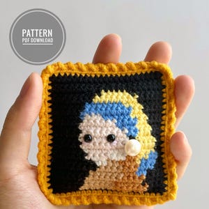 Puede incluir: Retrato de ganchillo de una niña con un pendiente de perla, enmarcado en hilo amarillo. El retrato está hecho con hilos de diferentes colores, incluyendo negro, blanco, azul, amarillo y marrón.