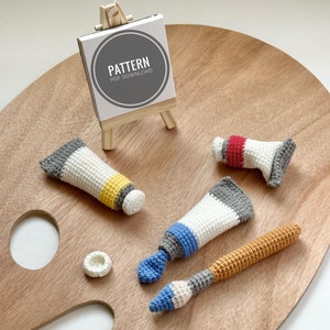 Może przedstawiać: Pluszowe zabawki w kształcie tubki z farbą i pędzla na drewnianej palecie artystycznej. Tabliczka z napisem "Pattern PDF Download".