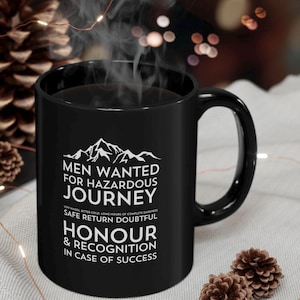 May include: Black coffee mug with white text that reads "Men Wanted for Hazardous Journey Low Wages, Bitter Cold, Long Hours of Complete Darkness Safe Return Doubtful Honour & Recognition in Case of Success"