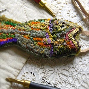 May include: A colorful, hand-stitched rug with a fish shape, made from various fabrics and yarns. Two wooden tools for rug hooking are also pictured.