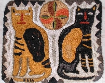 May include: A colorful rug with two stylized cats and a circular design in the center. The cats are black, brown, and orange, and the circle is green, orange, and brown.