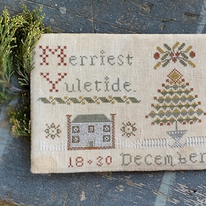 May include: Cross-stitch sampler featuring the text "Merriest Yuletide" and a small house, a Christmas tree, and the date "18*20 December".