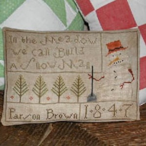 May include: A cross-stitch sampler with a snowman holding a shovel and the text "In the meadow we call built a snowman" and "Paron Brown 1847".