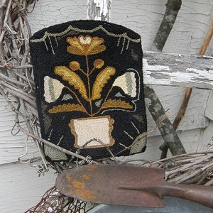 May include: A black rug with a yellow and white floral design. The rug is framed with a white border and has a white pot with a yellow flower in the center.