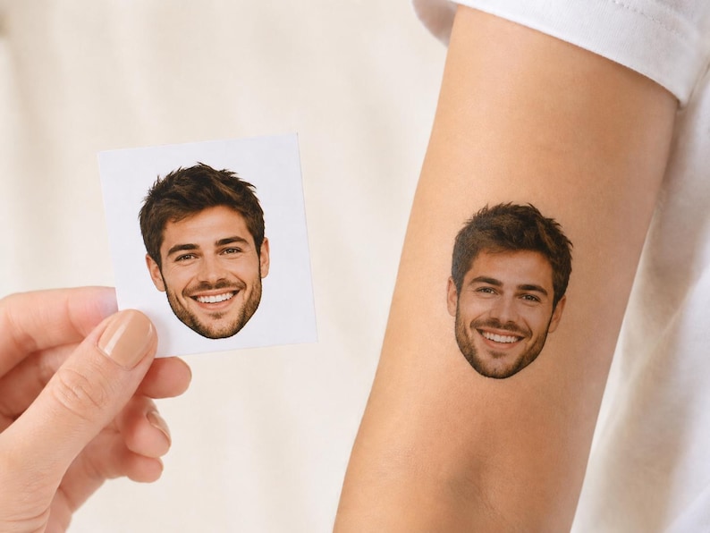 May include: A temporary tattoo featuring a realistic color portrait of a smiling person with dark hair and a beard, shown applied to skin alongside a square white paper card displaying the identical facial image for comparison and reference.