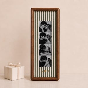 May include: A tall, rectangular wooden picture frame with a dark brown finish, containing a vertical strip of four black and white photos of a couple. The background inside the frame features green and white vertical stripes with the gold letters A and J.