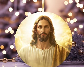 May include: Round Christmas ornament featuring a portrait of Jesus Christ. The image shows Jesus with long brown hair, a beard, and a white robe with a gold shawl. The ornament hangs from a gold ribbon, with a blurred background of Christmas lights.